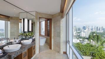 Un baño moderno con dos lavamanos, un espejo grande y vistas a la ciudad.
