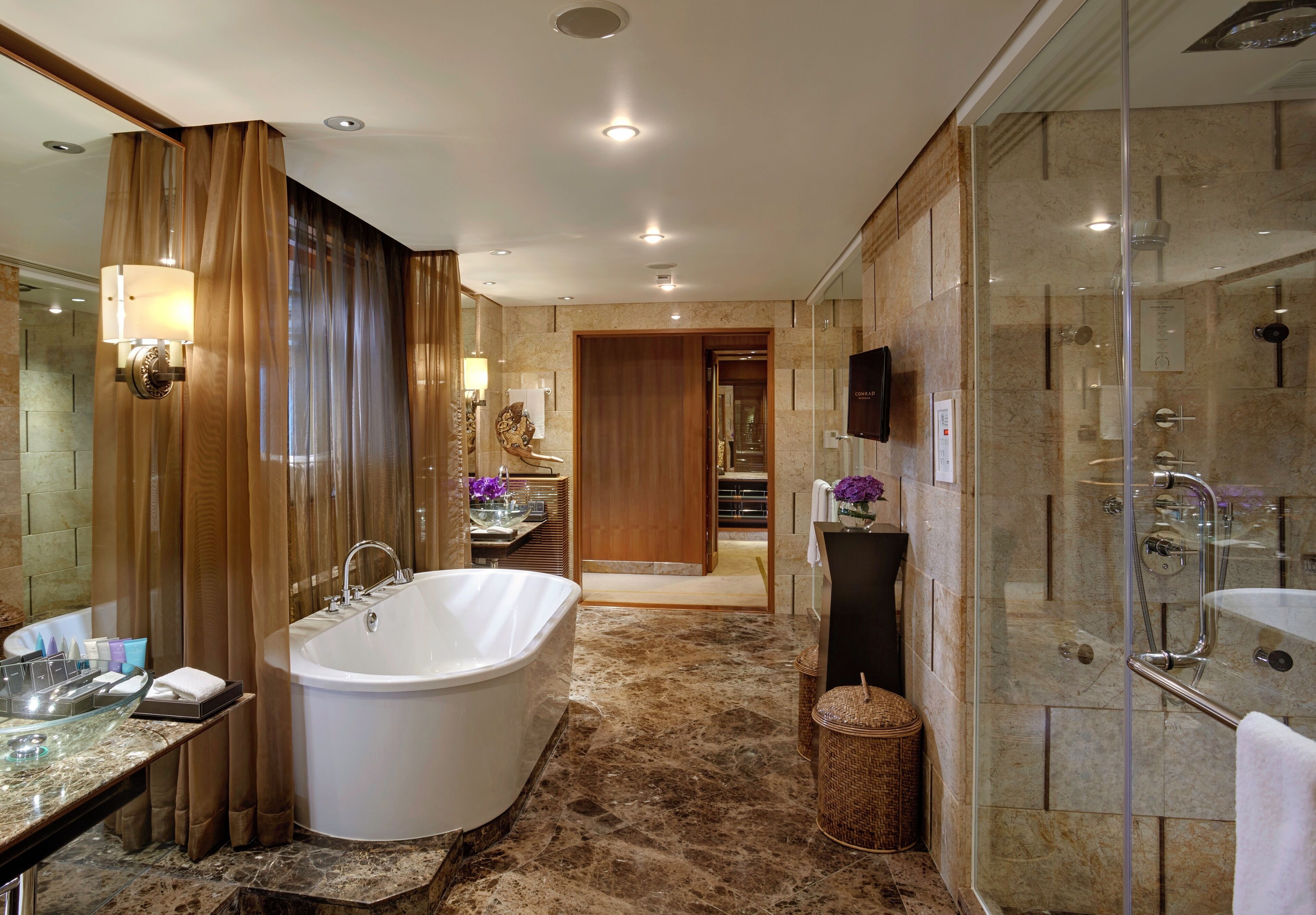 A modern bathroom with a freestanding bathtub, a glass-enclosed shower, and a marble-tiled floor.
