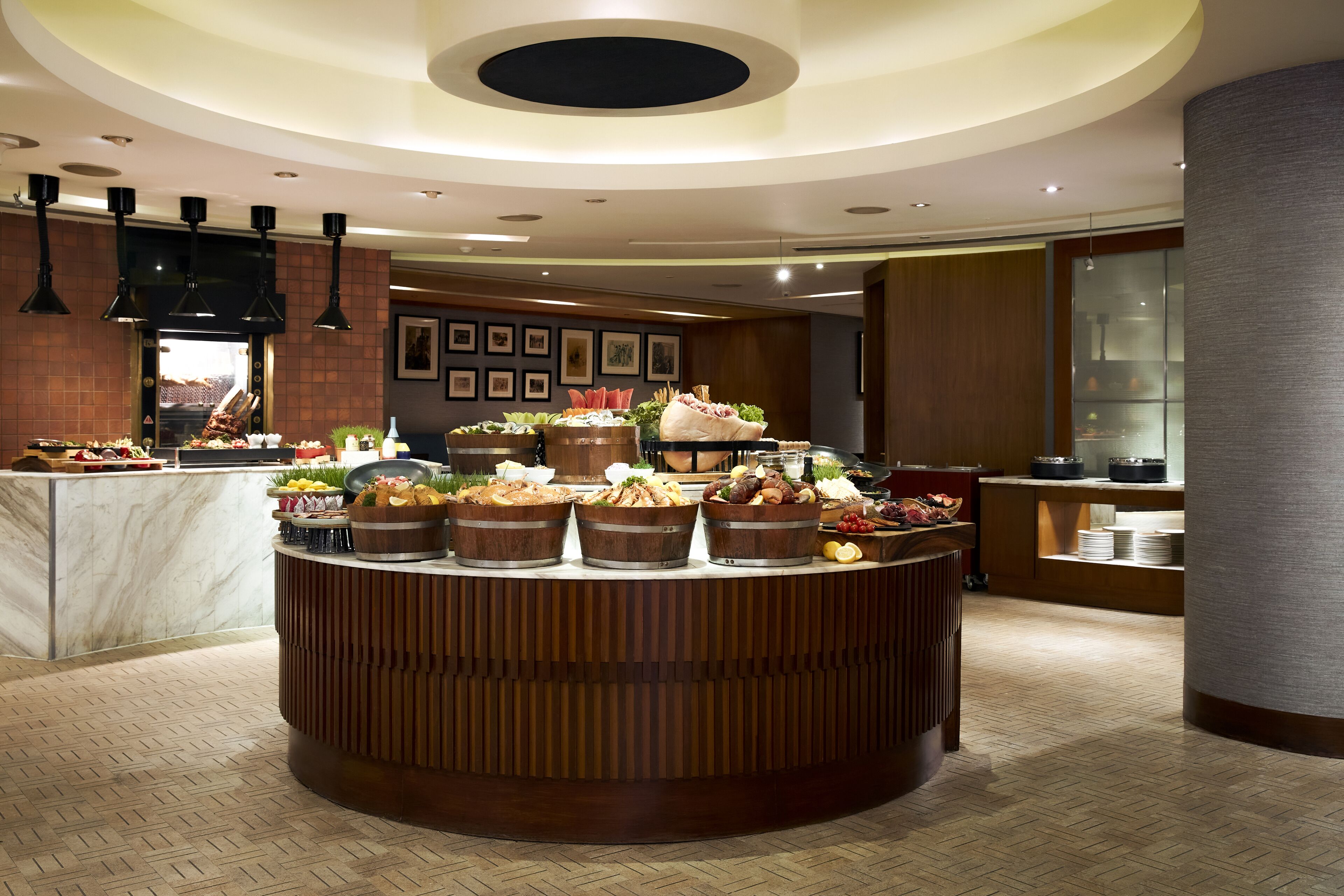 A buffet setup with various food items, a wooden counter, and a modern ceiling design.