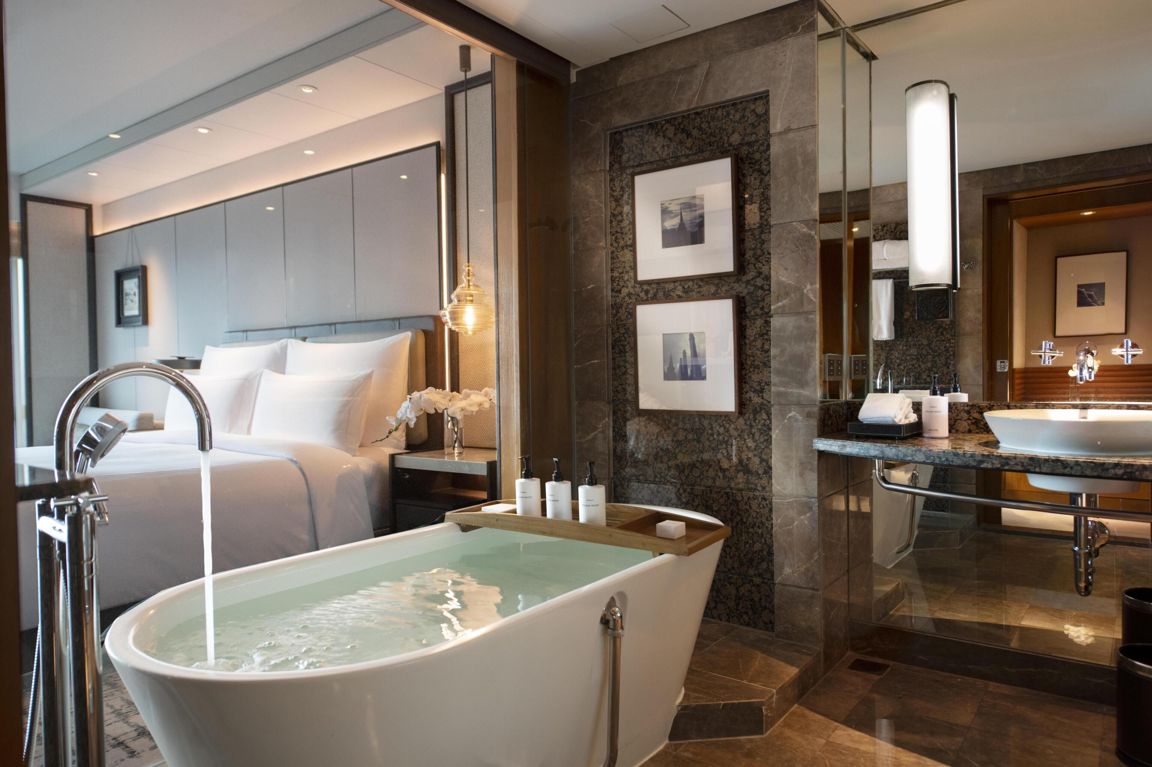 Un baño moderno con una bañera independiente, un espejo grande y un tocador con lavamanos.