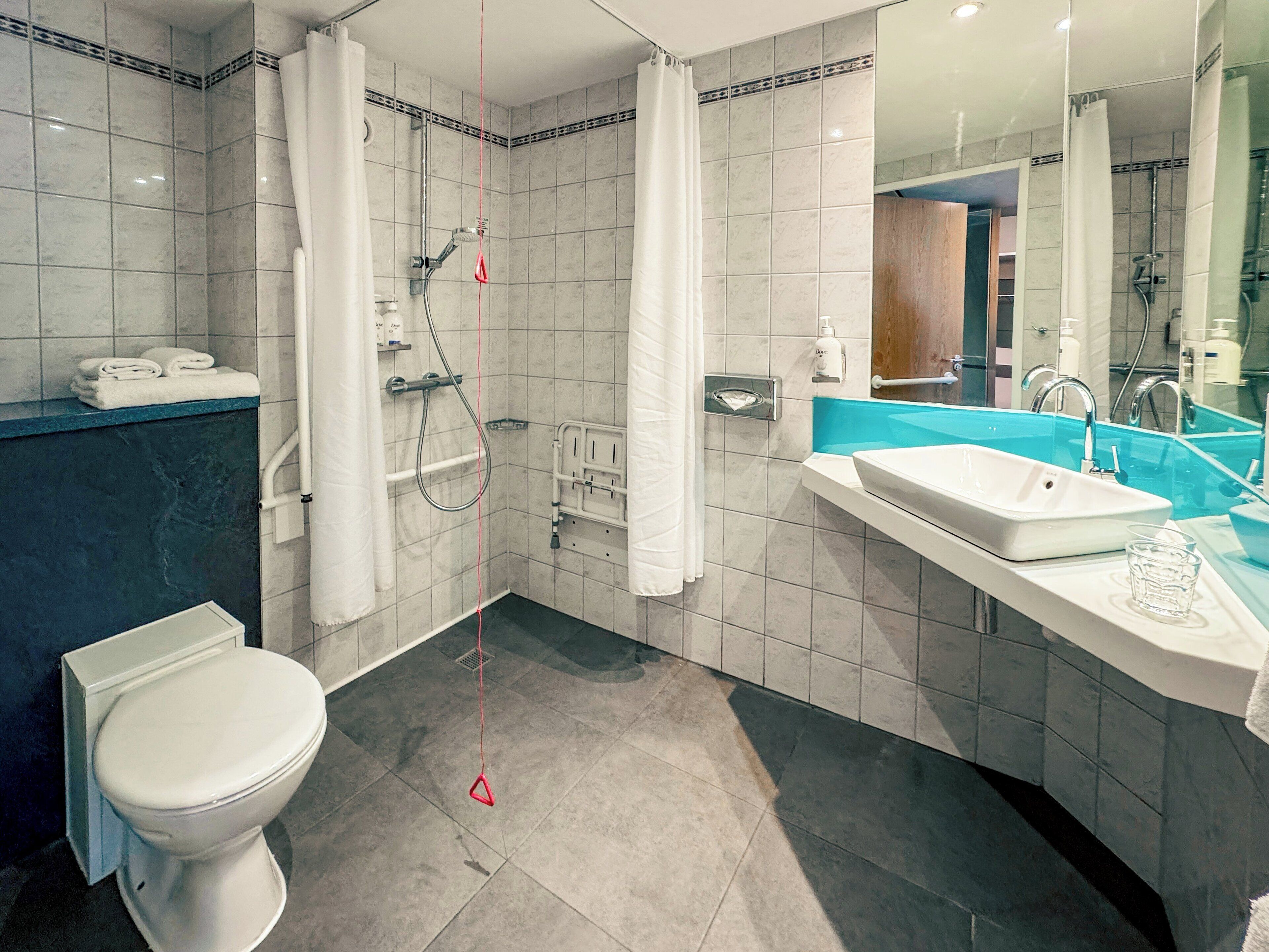 A modern bathroom with a shower, toilet, and sink.