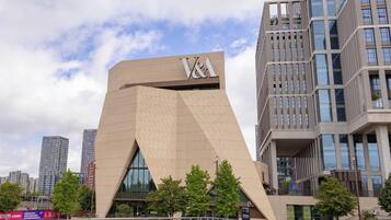 A modern building with a prominent V&A logo, surrounded by other high-rise structures and trees.