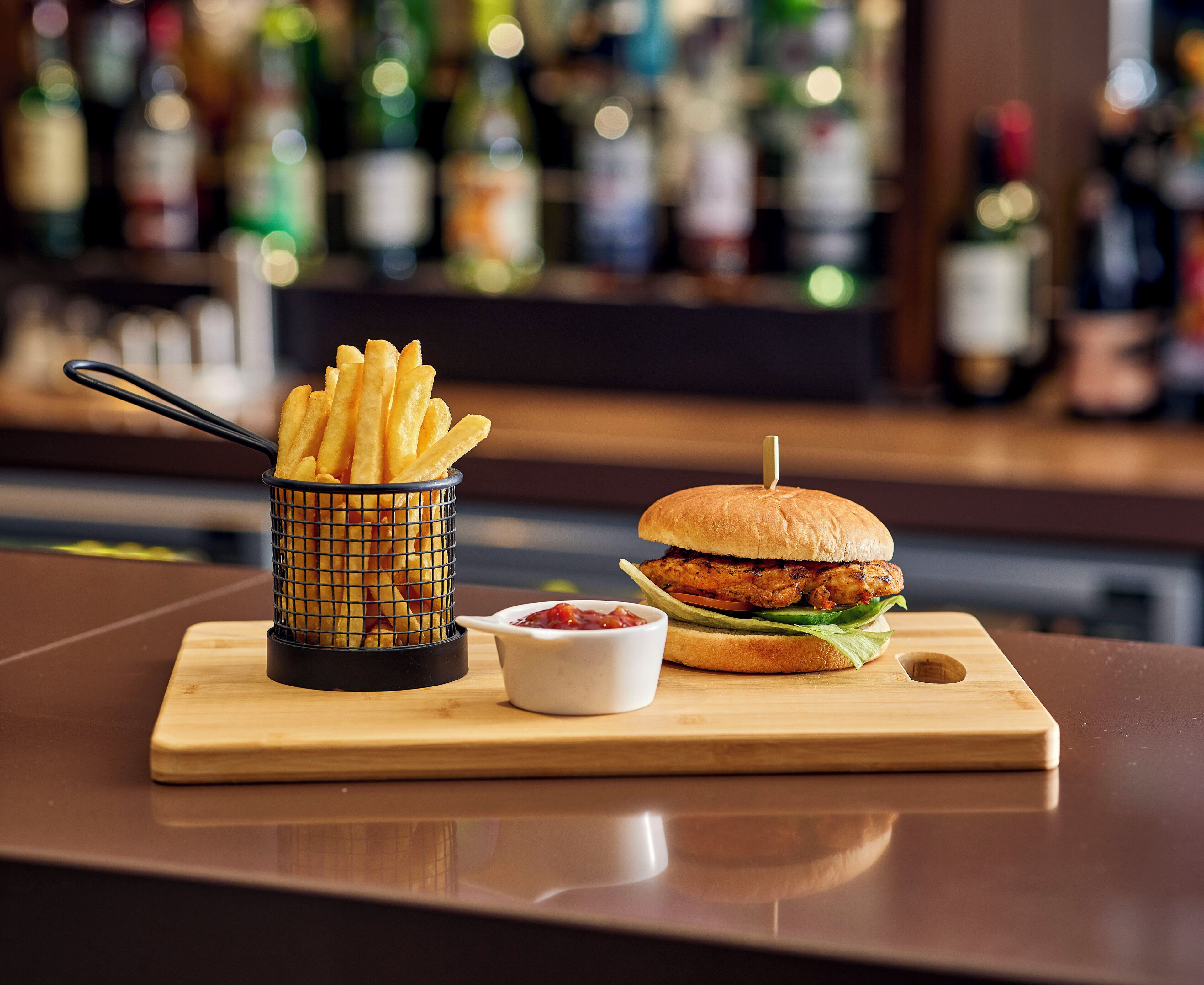 Eine Mahlzeit mit Pommes, Ketchup und einem Burger auf einer Holzplatte.
