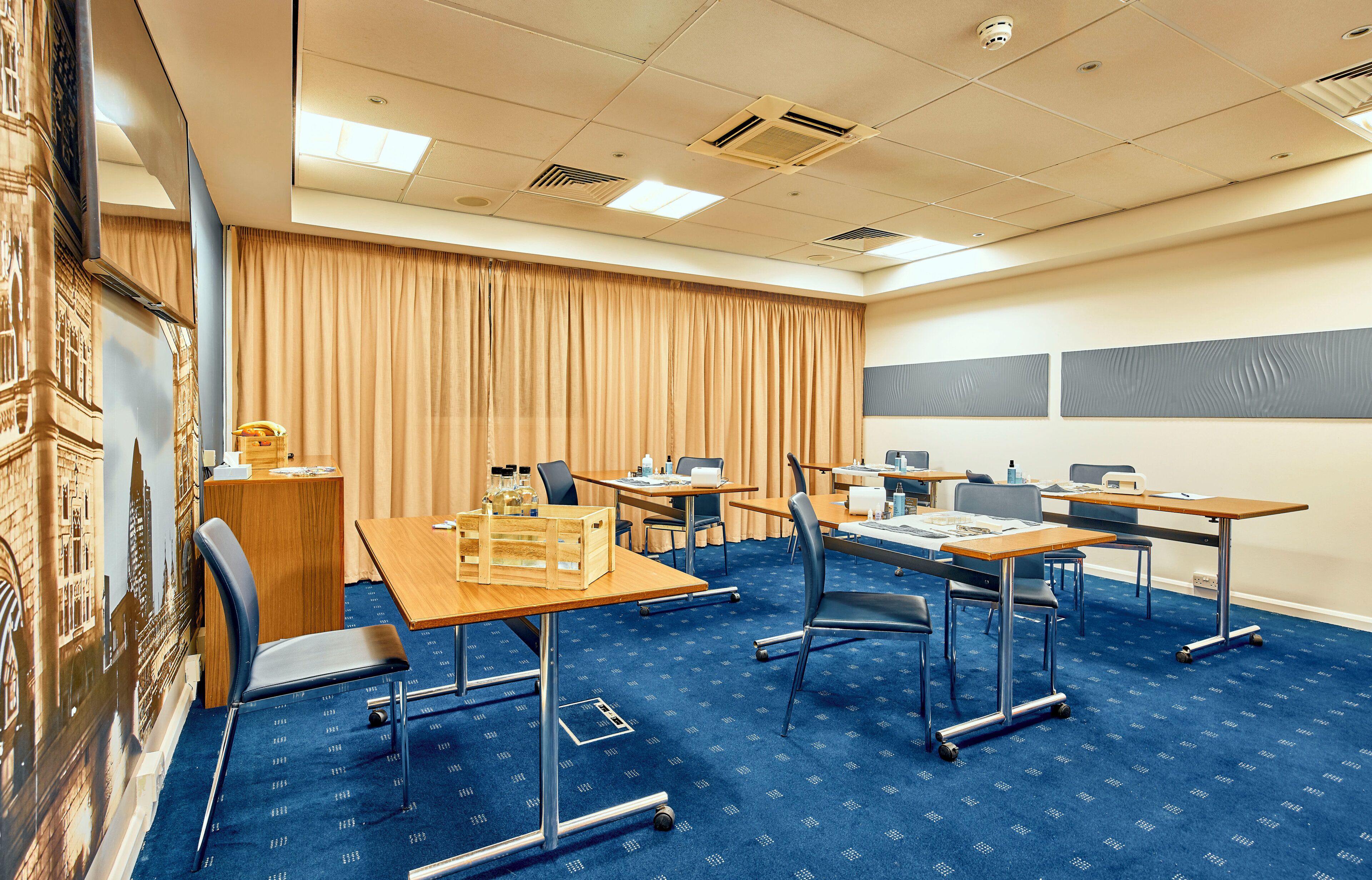A conference room with tables, chairs, a projector screen, and a large window with curtains.