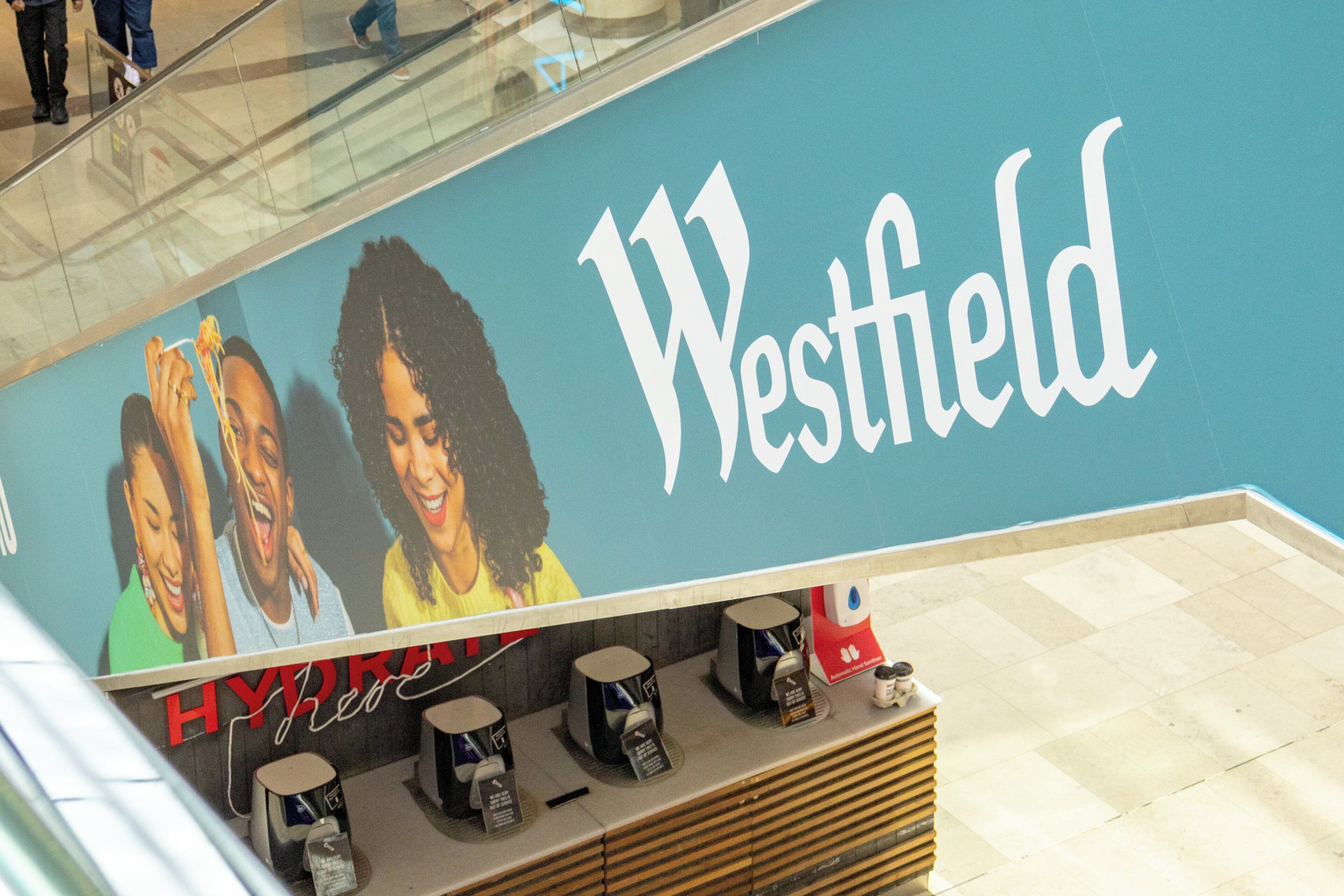 Een Westfield winkel met een grote reclame waarin drie lachende vrouwen te zien zijn.