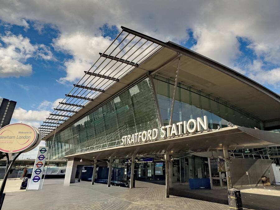 Een modern treinstation met een grote glazen gevel en een opvallend stationsbord.