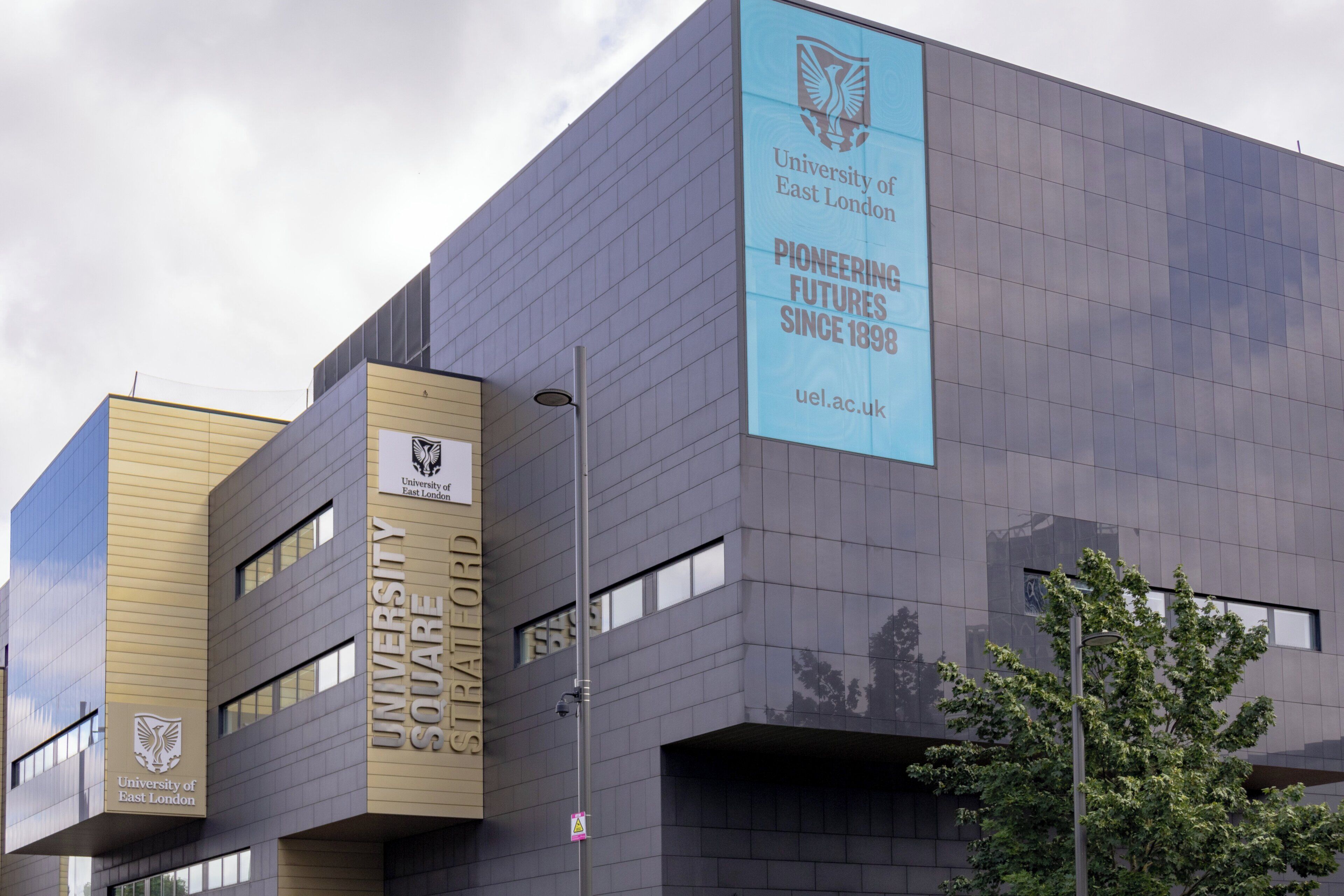 Un edificio moderno con el logotipo de la Universidad de East London y un cartel que dice 'Futuros Innovadores Desde 1898'.