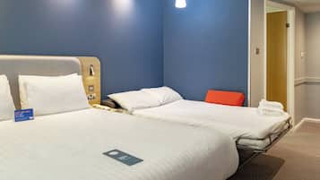 Quarto de hotel com duas camas, uma cabeceira de madeira, uma cadeira vermelha e uma porta que dá para outro quarto.