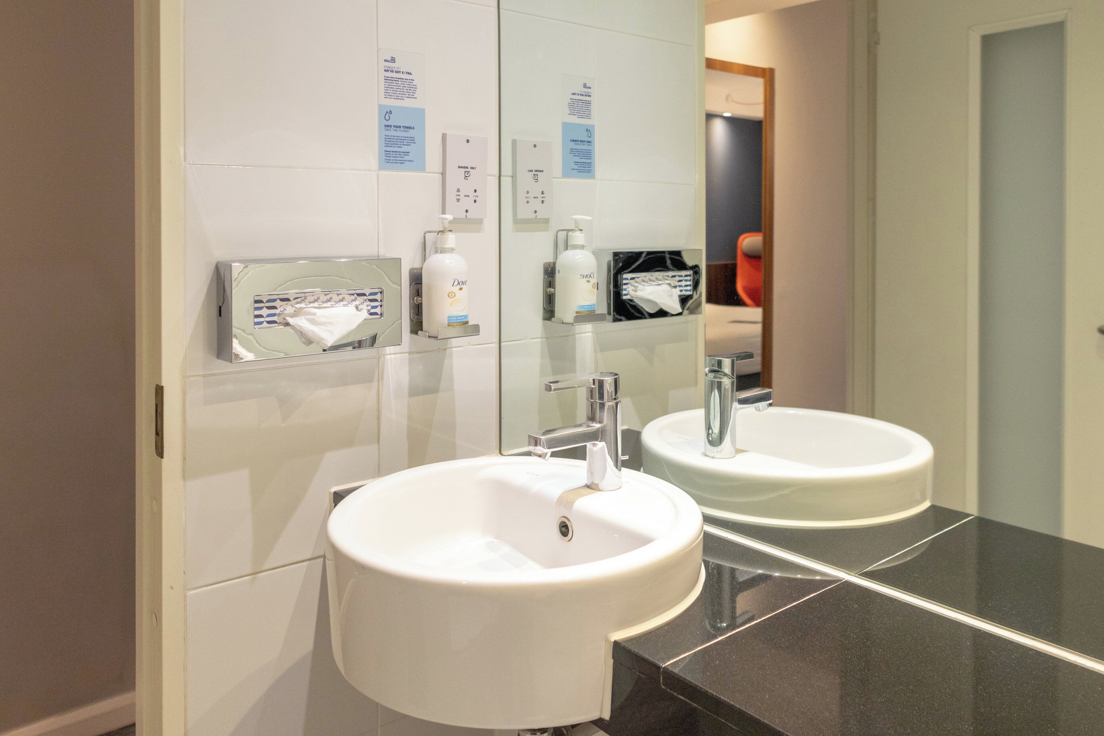 A modern bathroom with two sinks, a mirror, and various toiletries.