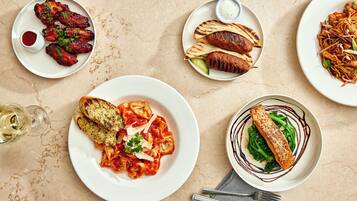 A table with various dishes, including pasta, grilled meats, and a fish fillet, suggesting a dining setting.