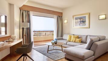 Ein modernes Hotelzimmer mit Balkon, einer Couch, einem Schreibtisch und einem Sessel.