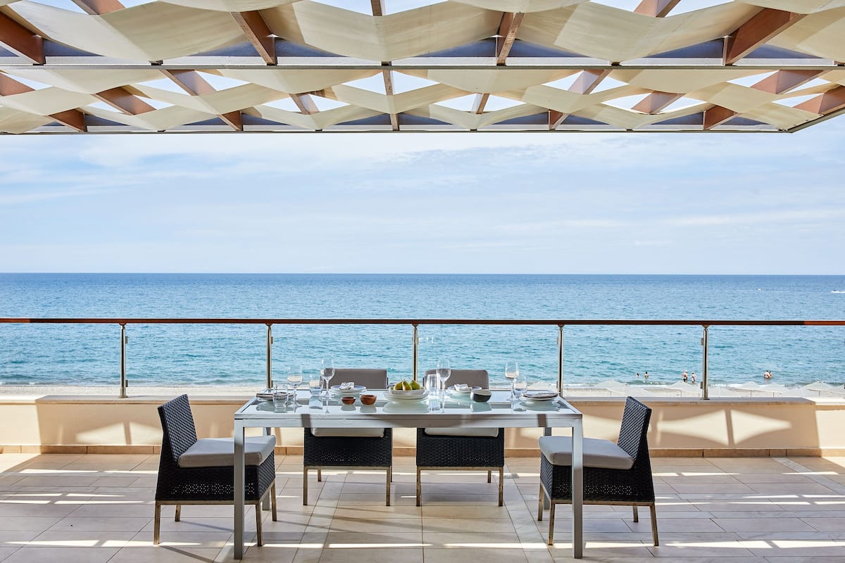 A dining table set for four with a view of the sea.