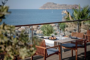 A dining area with a table set for two, overlooking a coastal view.