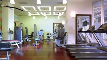 Un gimnasio con cintas de correr, máquinas de pesas y pesas libres.