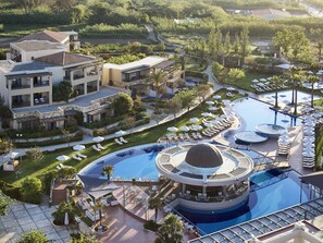A resort with a large pool, multiple lounge areas, and a variety of outdoor seating arrangements. - Minoa Palace Resort (Platanias)