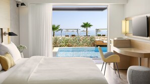 Habitación de hotel con cama, escritorio, televisor y vista a la piscina y la playa.