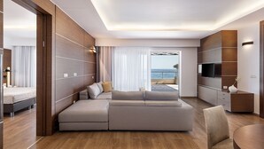 Habitación de hotel moderna con un sofá grande, un televisor y vistas al mar.