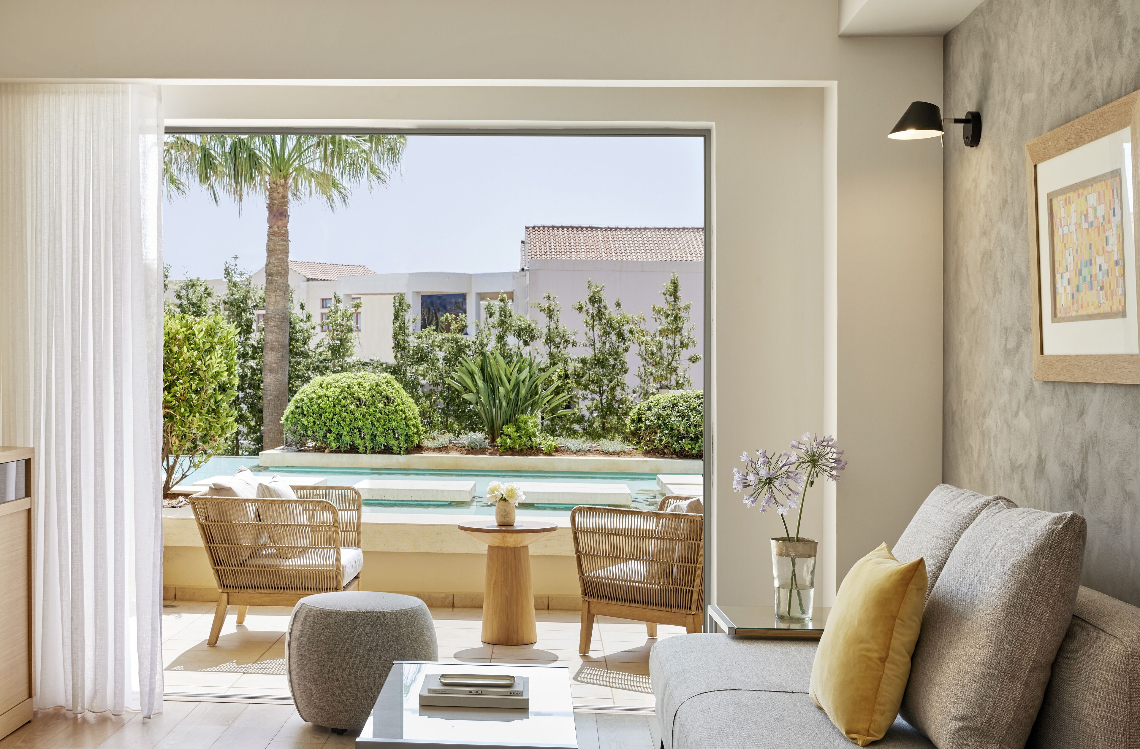 A modern living room with a view of a swimming pool, outdoor furniture, and a framed artwork on the wall.