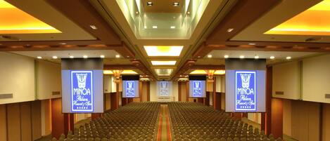A large conference room with rows of chairs, a central aisle, and a stage at the front.