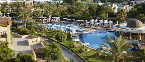 A resort with multiple swimming pools, sun loungers, and palm trees.
