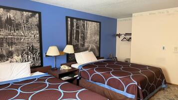 A hotel room with two beds, a nightstand with a lamp, a telephone, and a framed picture on the wall.