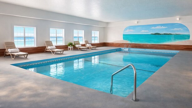 A swimming pool with lounge chairs, a view of the sea, and a ceiling mural. - Iron Mountain Inn & Suites MI US 2 (Iron Mountain)