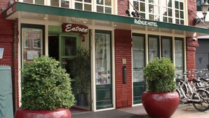 The Avenue Hotel with a brick facade, large potted plants, and a signboard. - Hotel Avenue (Amsterdam)