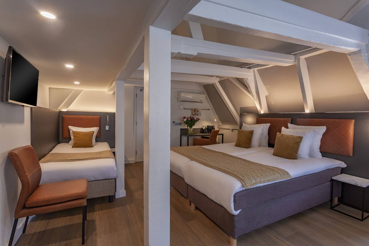 A modern hotel room with a large bed, a desk, and a TV.