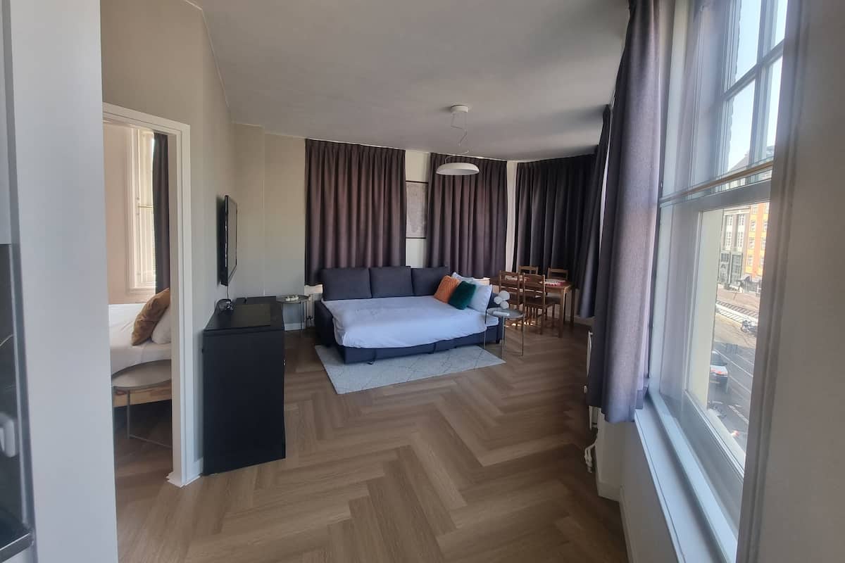 A modern hotel room with a large bed, a desk, a chair, and a dining table.