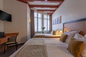 A hotel room with a bed, a desk, a chair, a TV, and a window with curtains. - Hotel Avenue (Amsterdam)