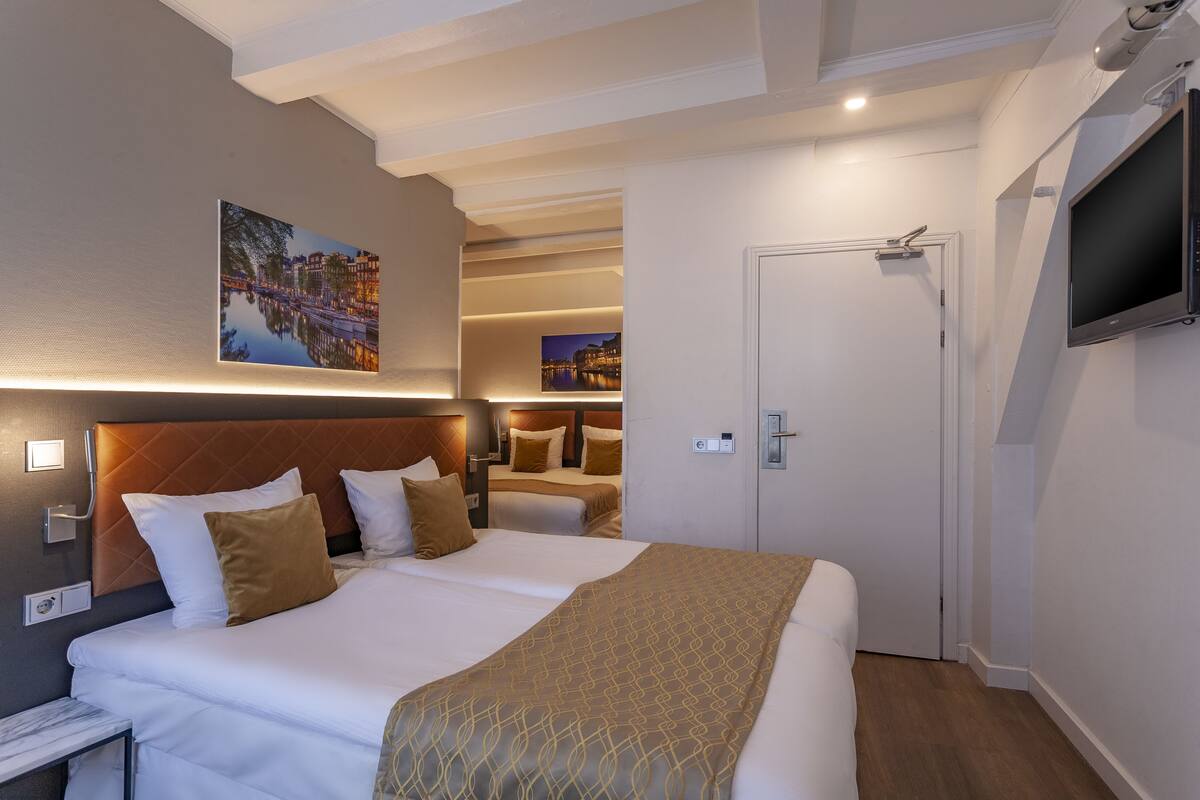 A hotel room with a large bed, a television, and a painting of a cityscape.