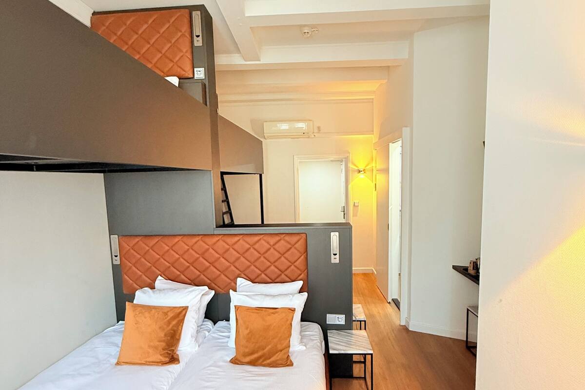 A hotel room with a large bed, a headboard, a bedside table, and a wardrobe.