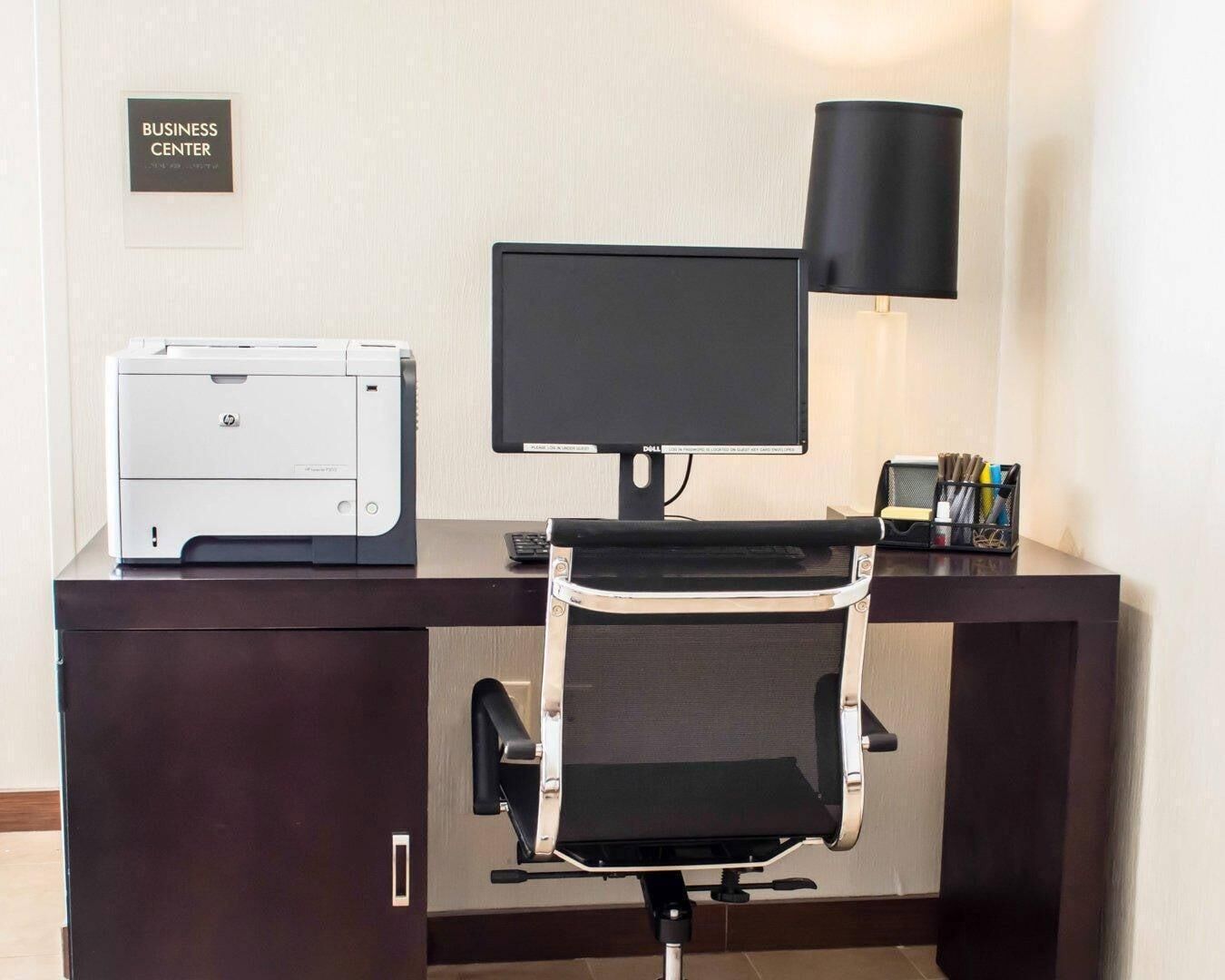 Escritorio de centro de negocios con una impresora, monitor y silla.