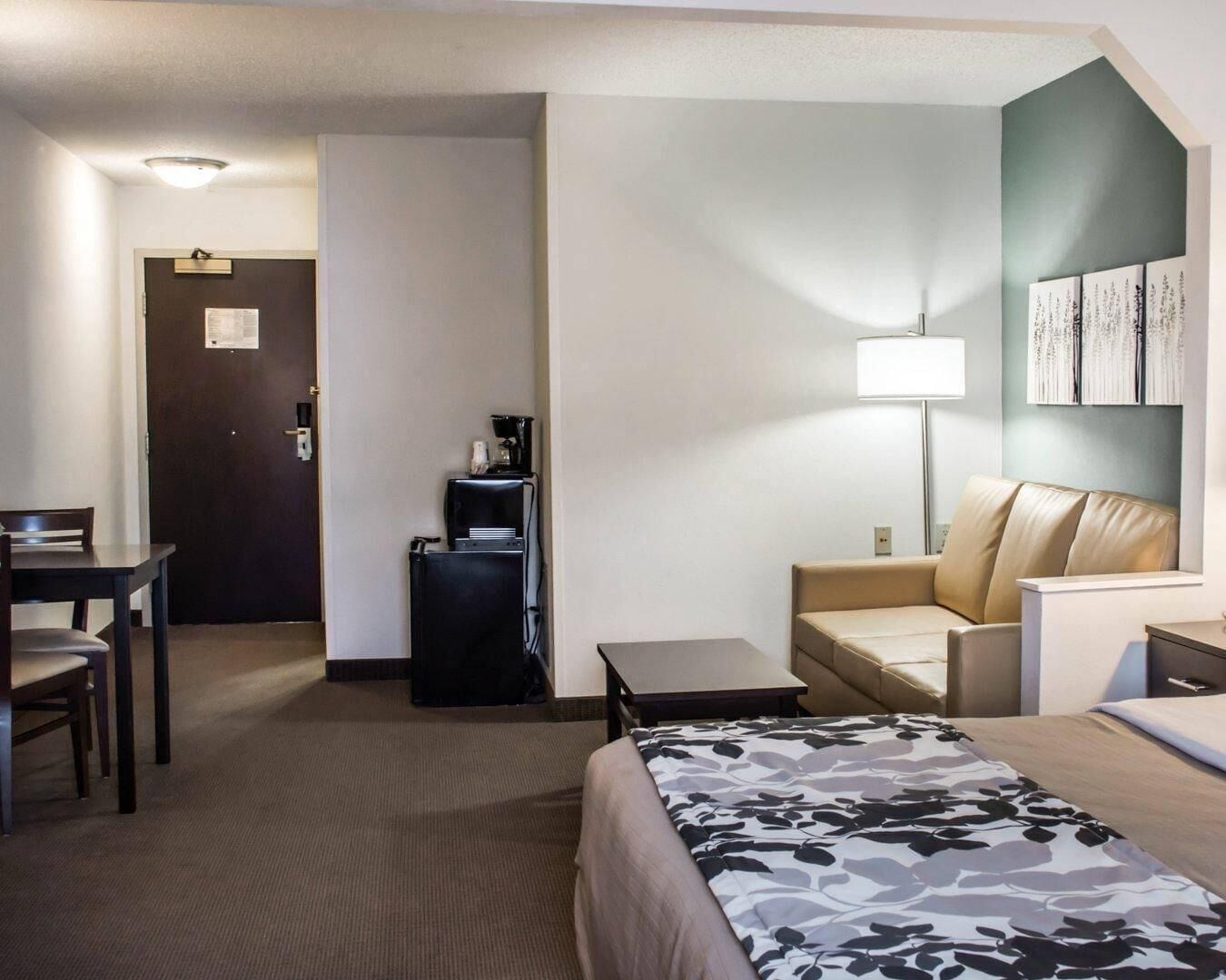 Hotelkamer met een bed, een bureau, een stoel, een bank, een koffieapparaat en een lamp.