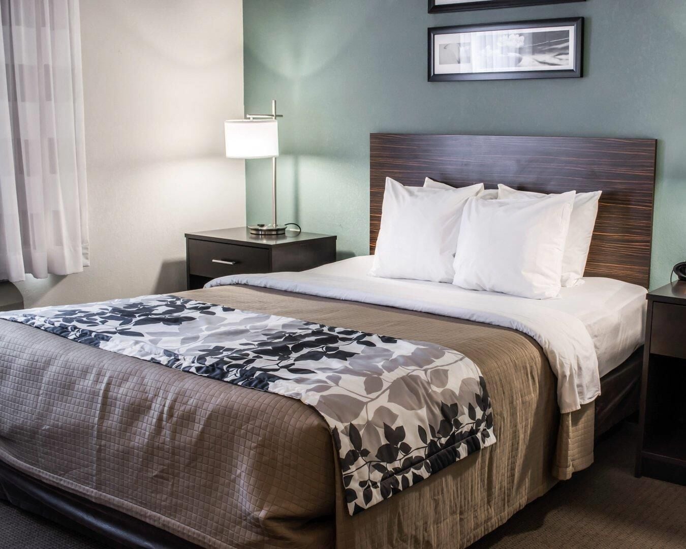 Une chambre d’hôtel avec un lit, une table de chevet, une lampe et un tableau accroché au mur.