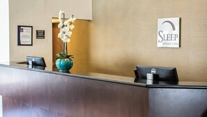 A reception desk with a sign that reads 'SLEEP INN & SUITES' and a framed certificate on the wall. - Sleep Inn & Suites Monticello (Charlottesville)