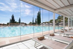 Una piscina techada, una piscina al aire libre de temporada, sombrillas