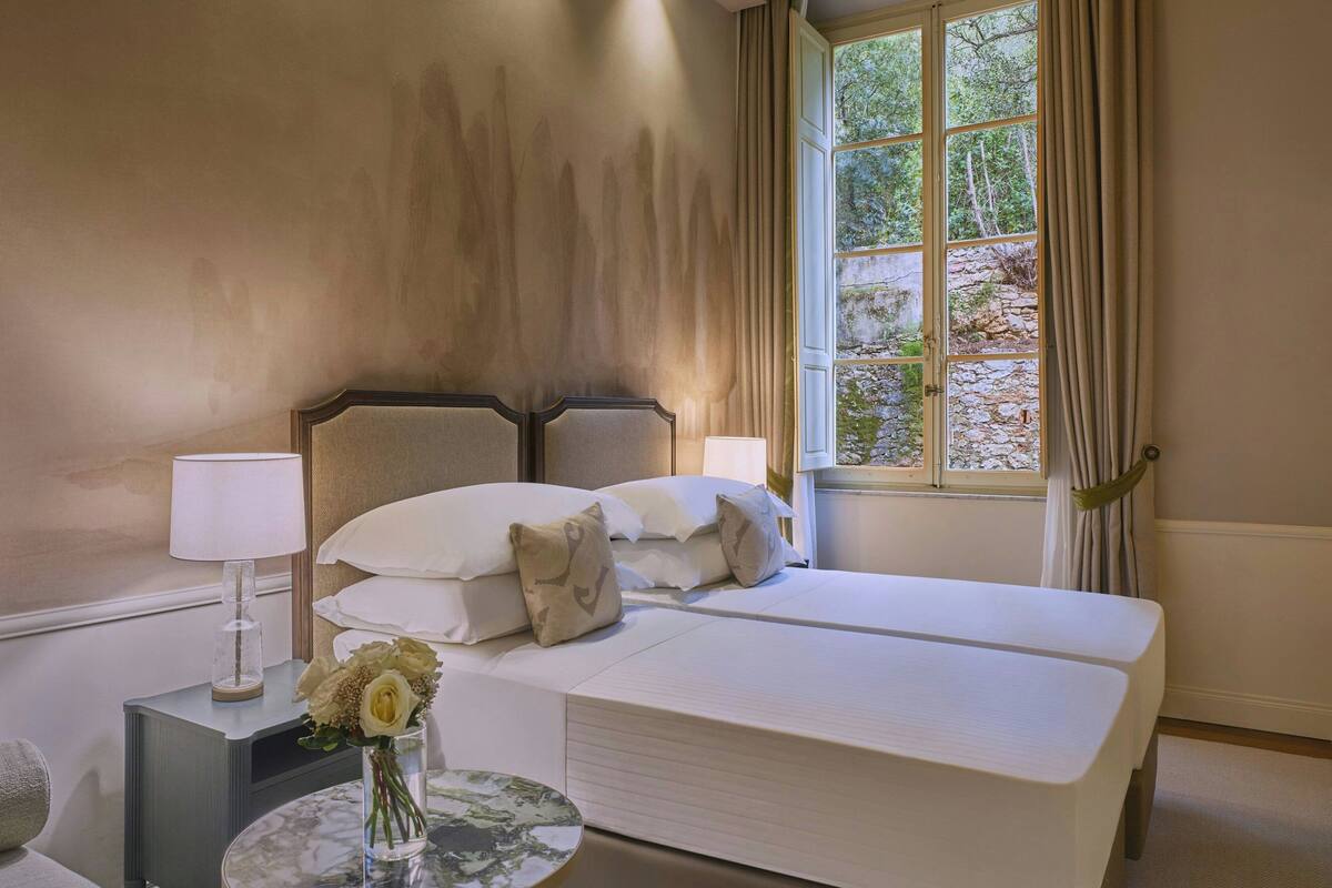 A neatly arranged bedroom with a bed, bedside tables, and a window with curtains.