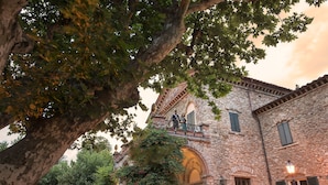 Un bâtiment en pierre doté d’un balcon, entouré d’arbres.