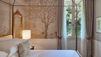 A bedroom with a canopy bed, a large mirror, a wall mural, and a window with curtains.