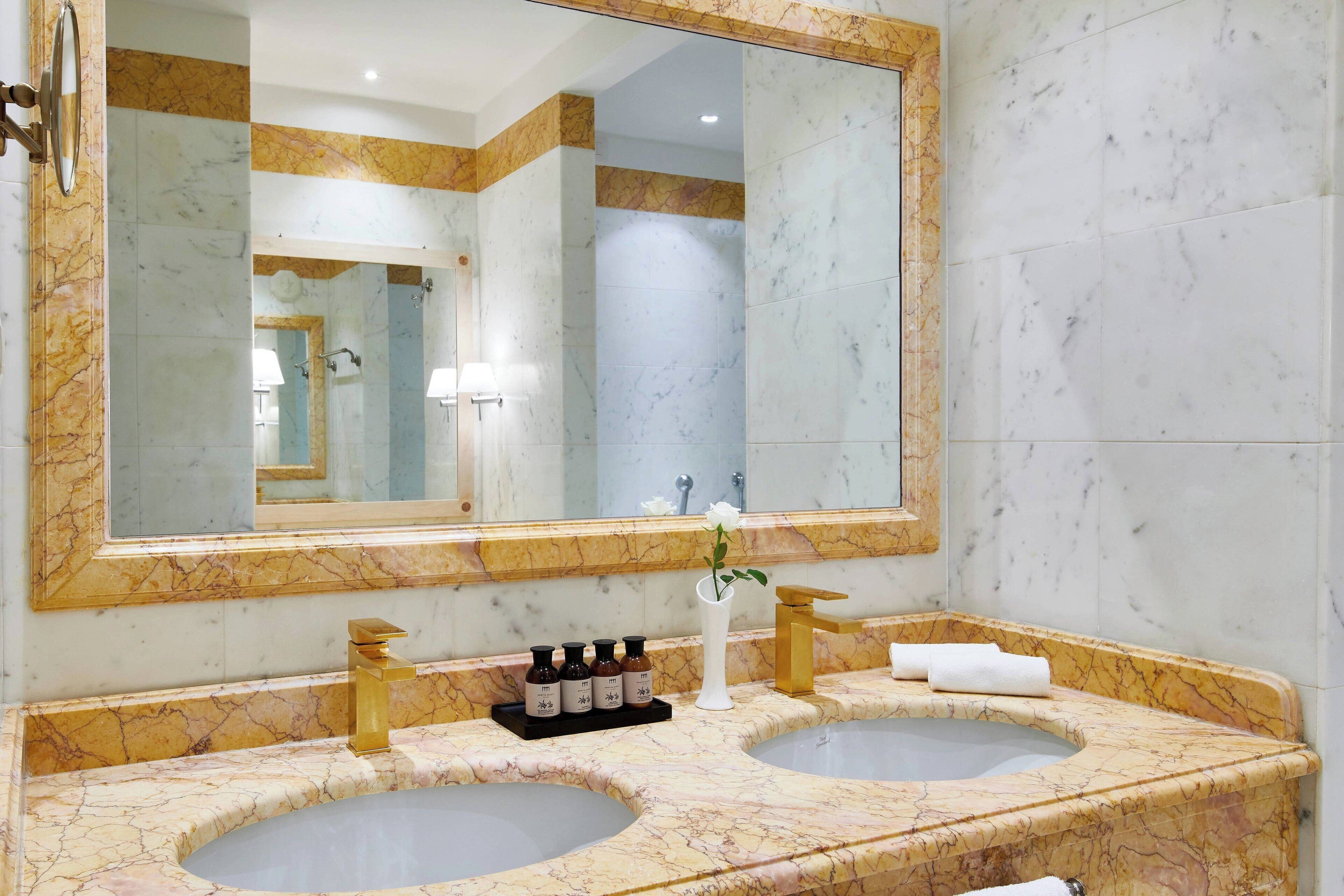 A bathroom with two sinks, a large mirror, and a vanity with toiletries.