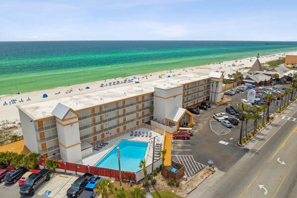 A hotel with a rooftop pool, beach view, and parking lot.