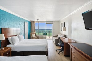 A hotel room with a large bed, a desk, a chair, and a television.