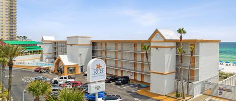A hotel with a pool, parking lot, and ocean view.