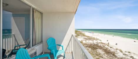 A balcony with turquoise chairs and a view of the beach.