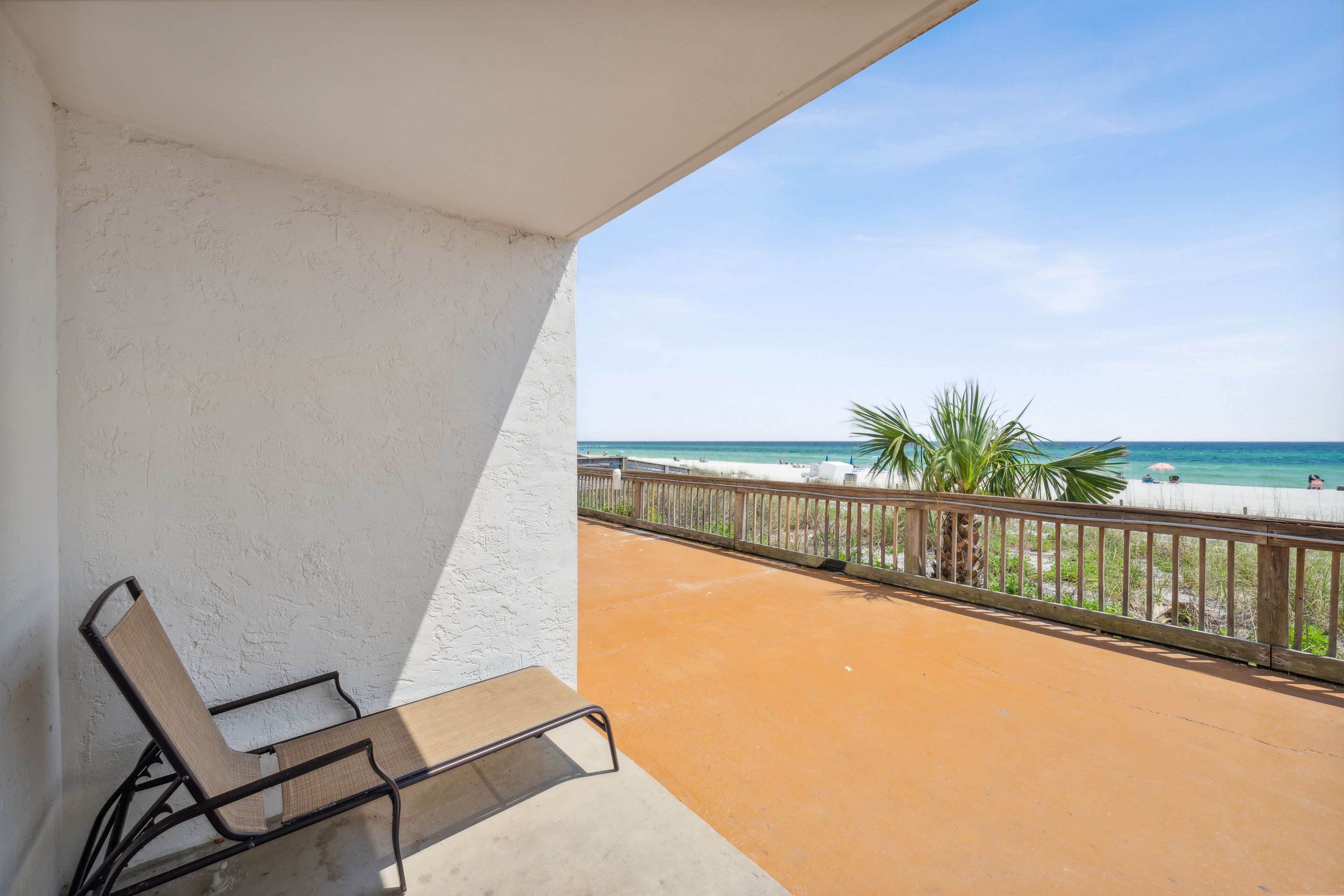 Een balkon met uitzicht op het strand, een stoel en een leuning.
