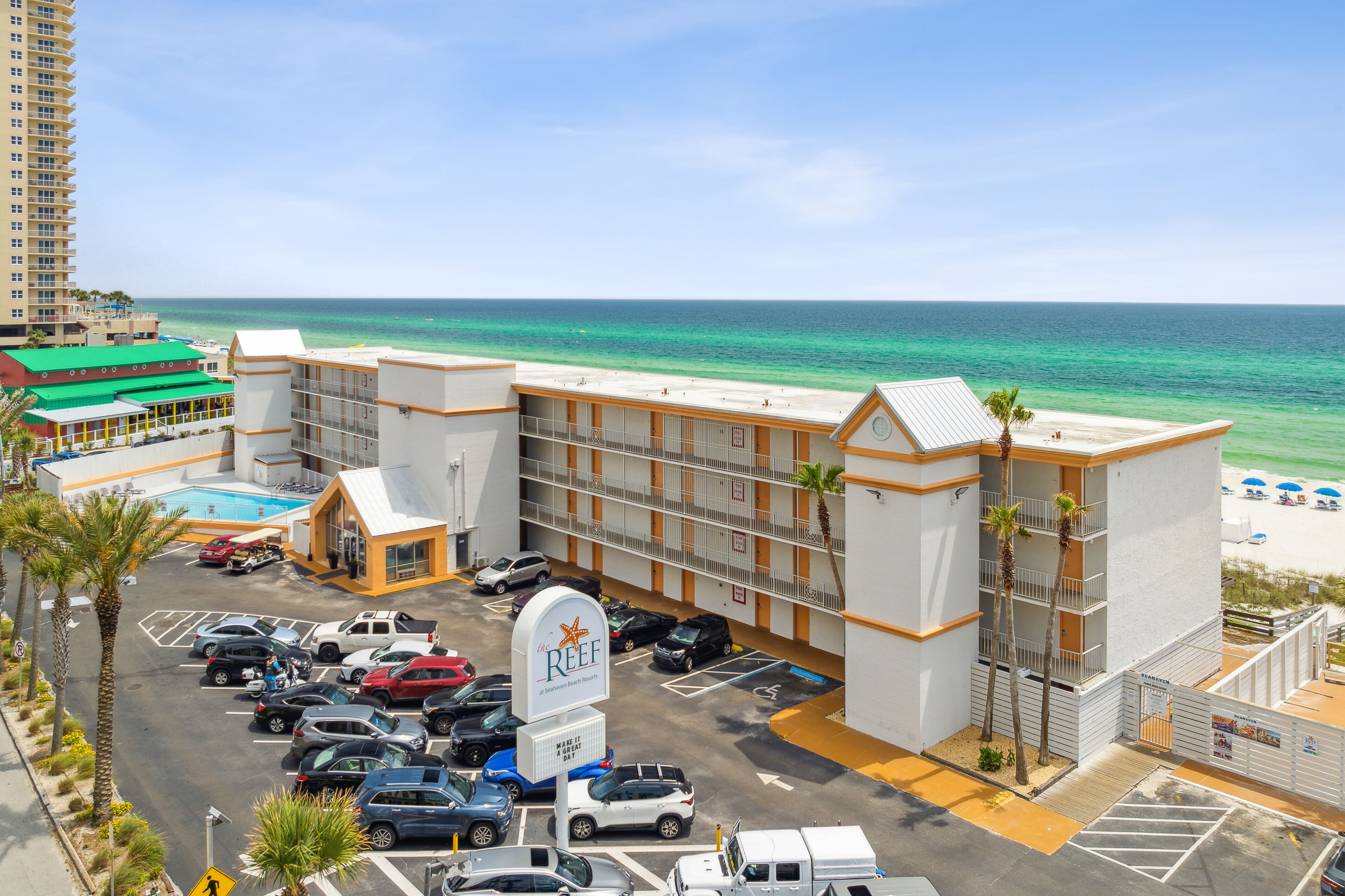 Un hotel con piscina, estacionamiento y vista al mar.