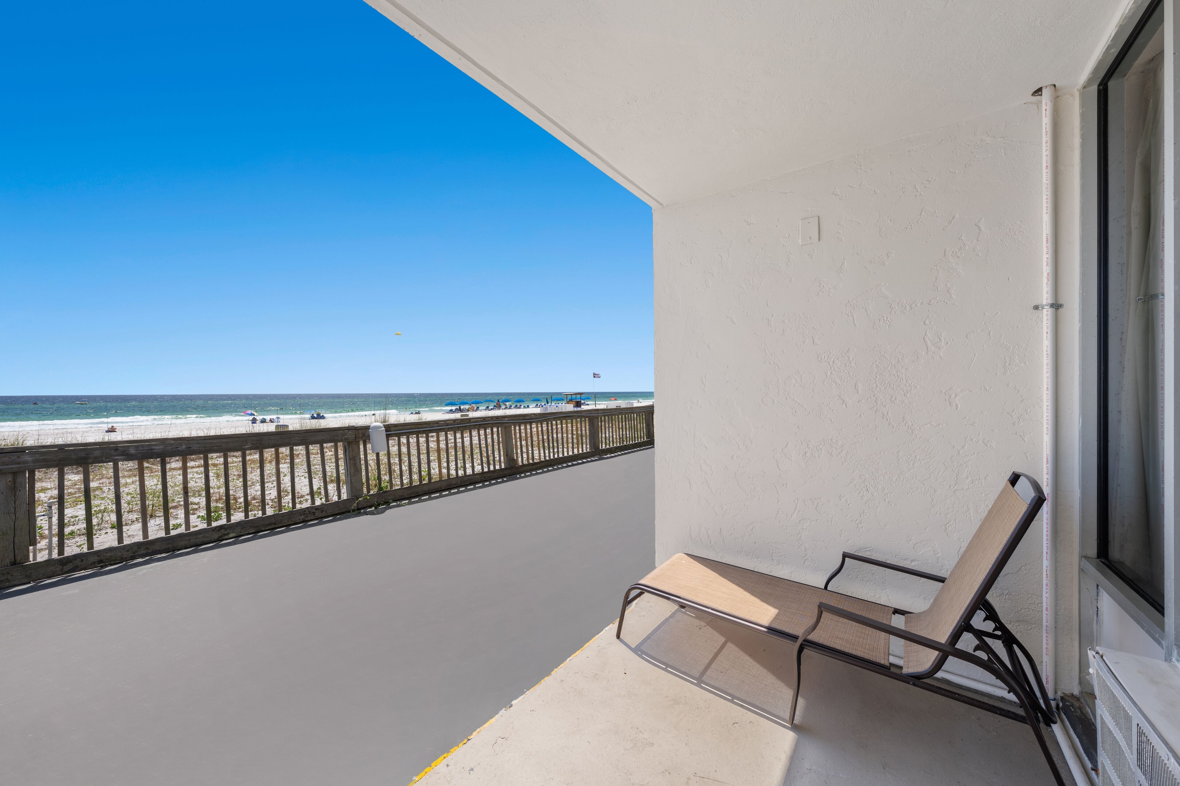 Un balcón con vista a la playa, una silla y una ventana.