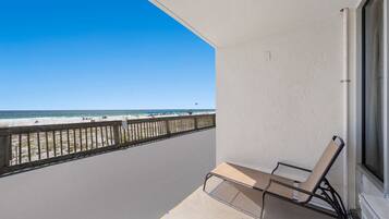 Un balcón con vista a la playa, una silla y una ventana.