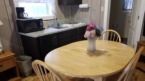 A compact kitchen with a microwave, sink, and wooden dining table with chairs. - Nevada City Inn (Nevada City)